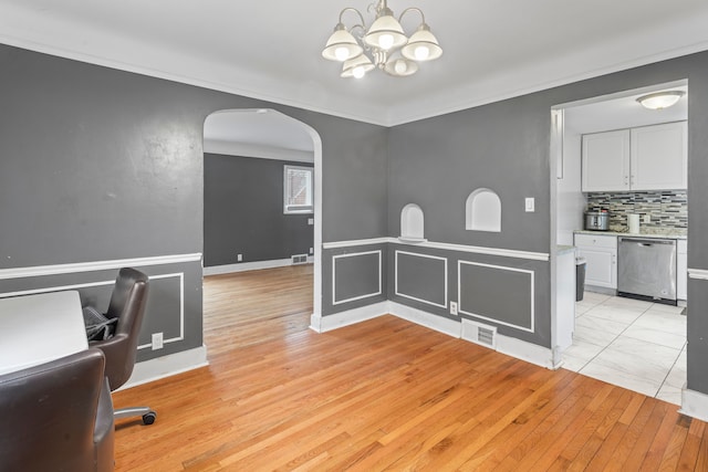 interior space with light wood-style floors, visible vents, arched walkways, and crown molding