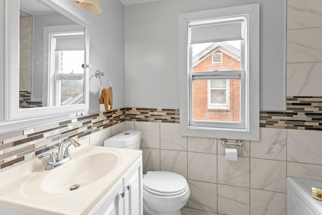 bathroom featuring tile walls, vanity, and toilet