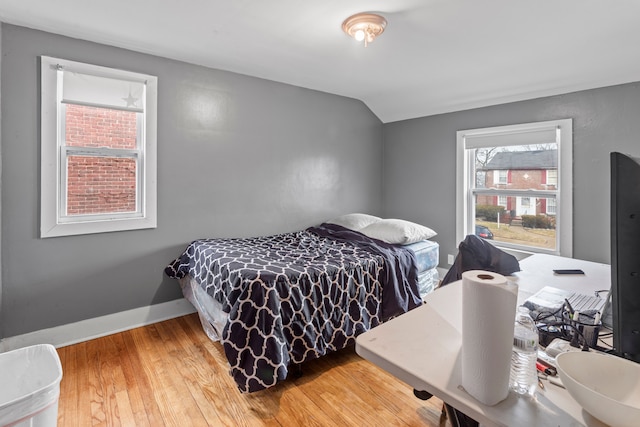 bedroom featuring baseboards, vaulted ceiling, and wood finished floors