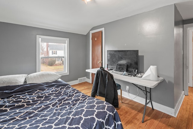 bedroom featuring lofted ceiling, wood finished floors, visible vents, and baseboards