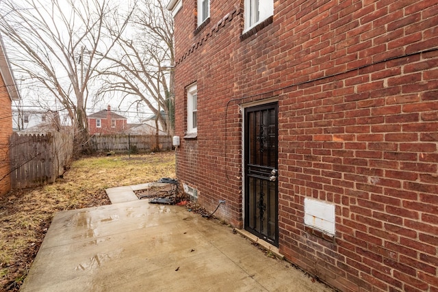 view of side of property with a patio area, fence, and brick siding