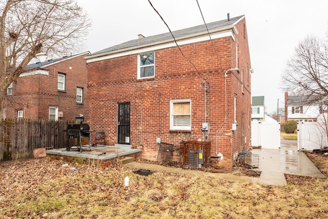 rear view of property featuring a patio area, fence, and brick siding