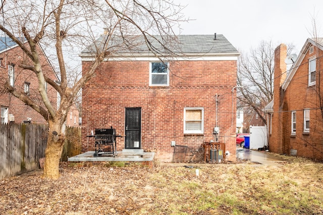 rear view of property with a patio area, fence, and brick siding