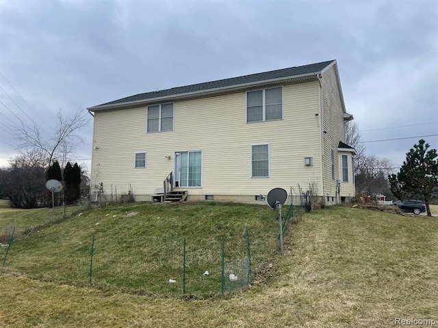 back of property featuring entry steps and a yard