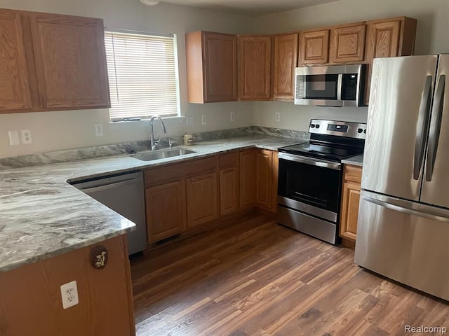 kitchen featuring wood finished floors, appliances with stainless steel finishes, and a sink