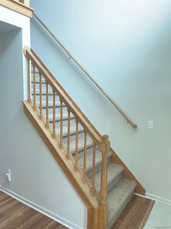 staircase with baseboards and wood finished floors