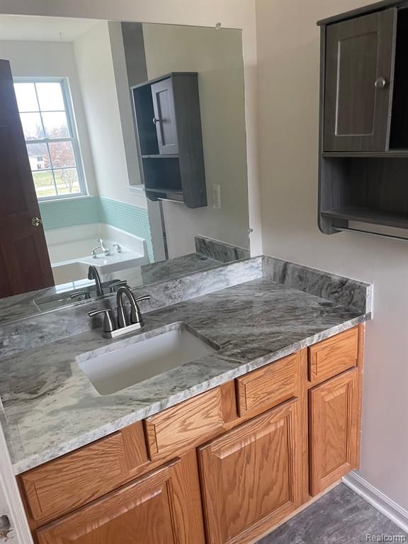 kitchen with brown cabinets, light stone countertops, and a sink