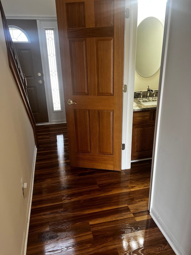 hallway with dark wood-style floors, baseboards, and a sink