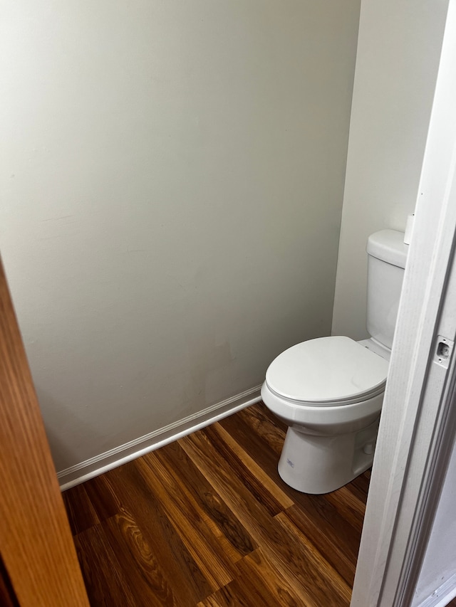 bathroom featuring toilet, wood finished floors, and baseboards