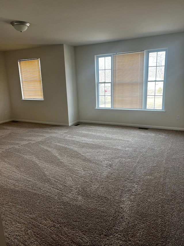 unfurnished room featuring visible vents, baseboards, and carpet flooring