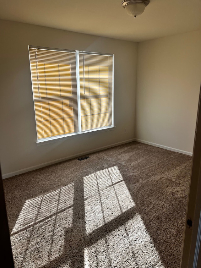 carpeted spare room featuring visible vents and baseboards