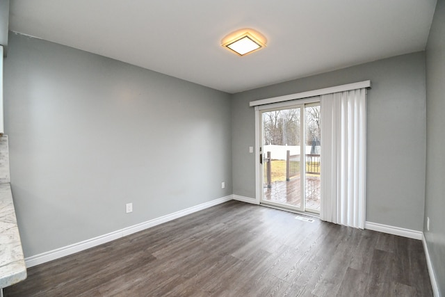 spare room featuring baseboards and dark wood-style flooring