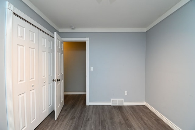 unfurnished bedroom featuring visible vents, baseboards, dark wood-type flooring, and a closet