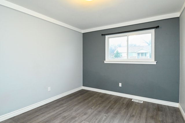 unfurnished room featuring dark wood-type flooring, visible vents, and baseboards