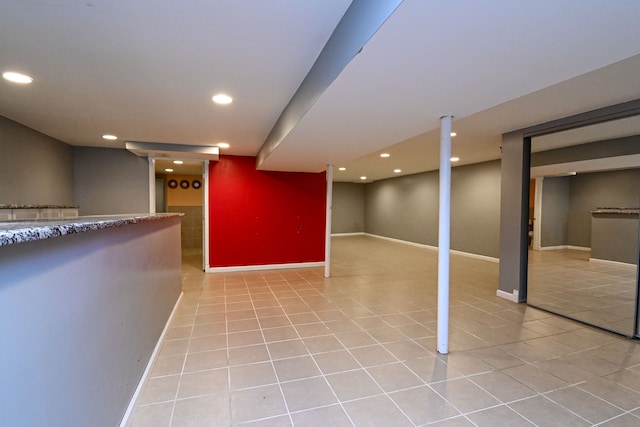 finished below grade area featuring light tile patterned flooring, recessed lighting, and baseboards