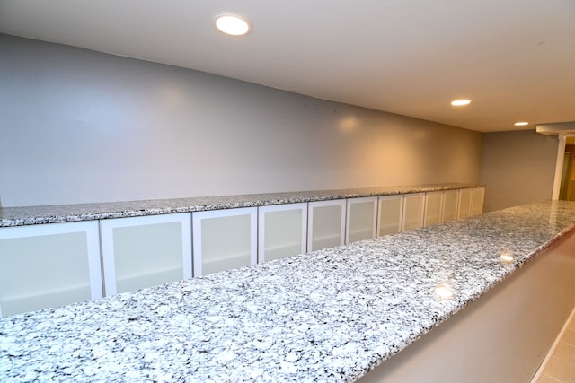 interior details featuring recessed lighting, glass insert cabinets, and light stone counters