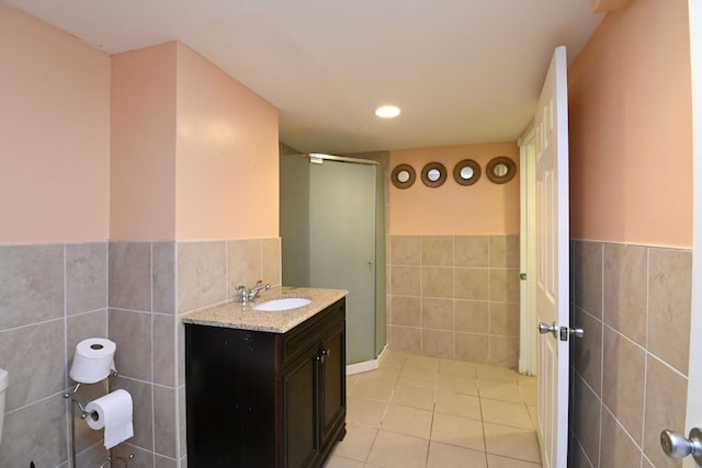 full bath featuring tile patterned flooring, a wainscoted wall, vanity, a stall shower, and tile walls