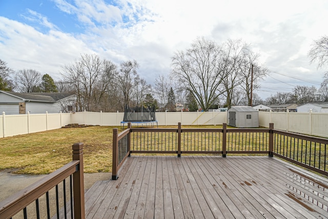 wooden deck featuring a lawn, a trampoline, a fenced backyard, a shed, and an outdoor structure