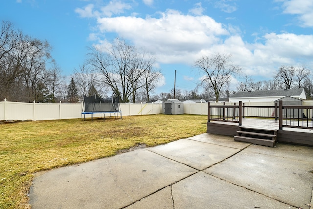 view of yard featuring a trampoline, a fenced backyard, an outdoor structure, a storage unit, and a patio