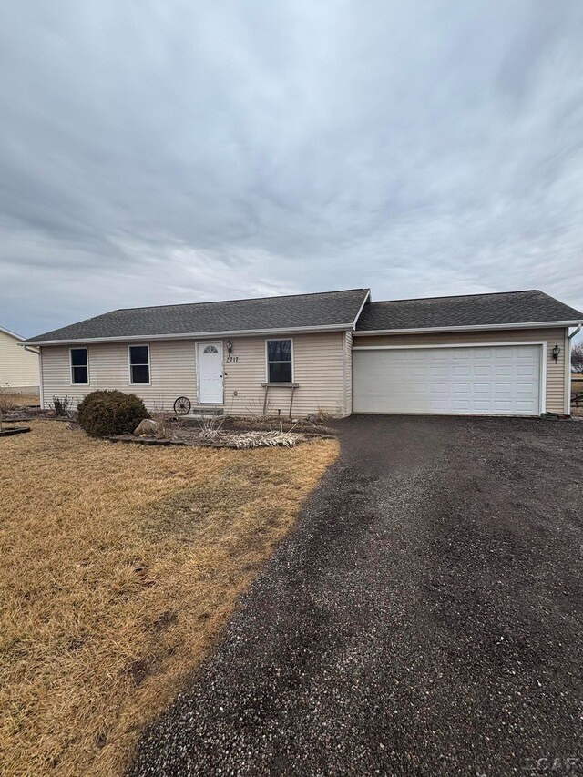 single story home featuring a garage, aphalt driveway, and a front yard