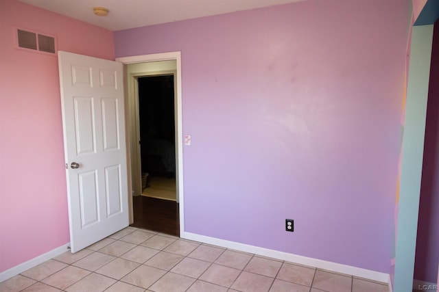 empty room featuring baseboards, visible vents, and light tile patterned floors