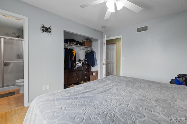bedroom featuring visible vents, wood finished floors, a closet, ceiling fan, and connected bathroom