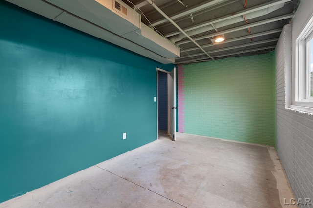 spare room with brick wall and concrete floors