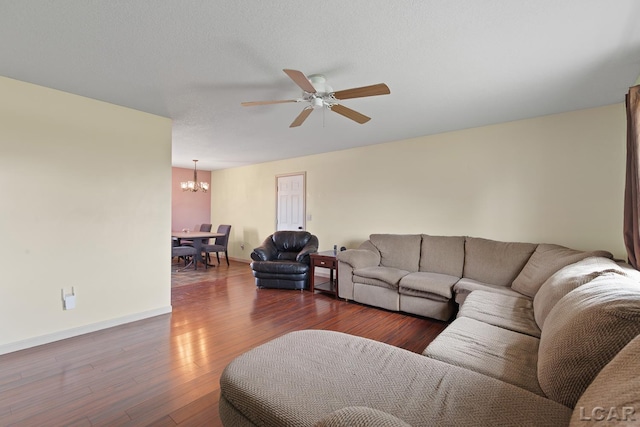 living room with ceiling fan with notable chandelier, baseboards, and wood finished floors