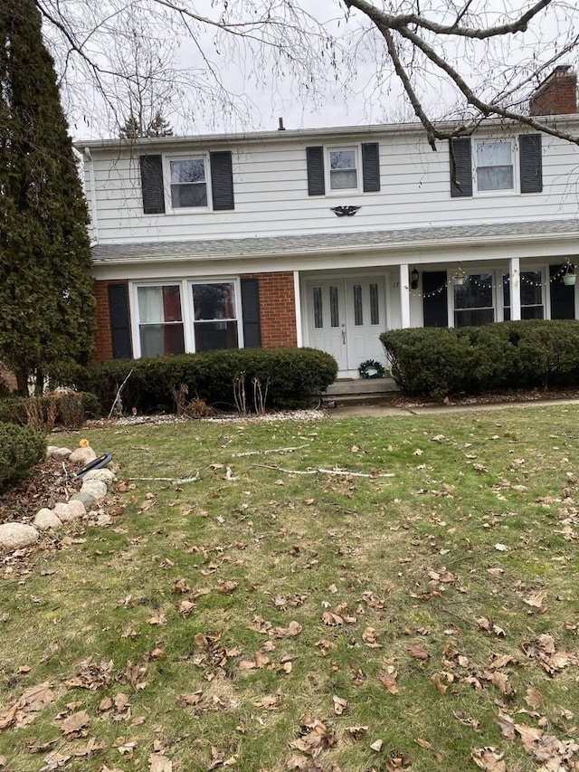 traditional-style home featuring brick siding, a porch, and a front yard