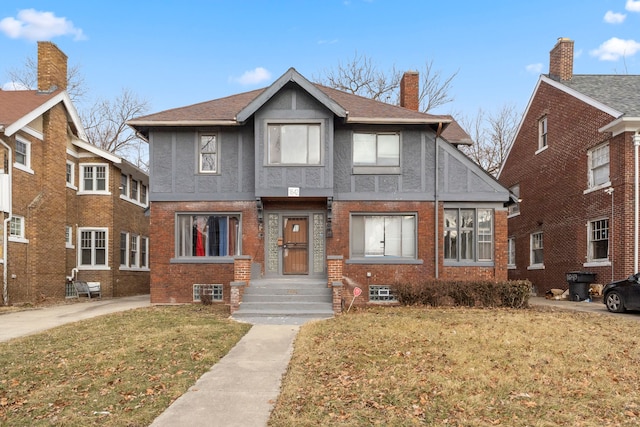 view of front of property featuring a front yard, brick siding, a chimney, and stucco siding