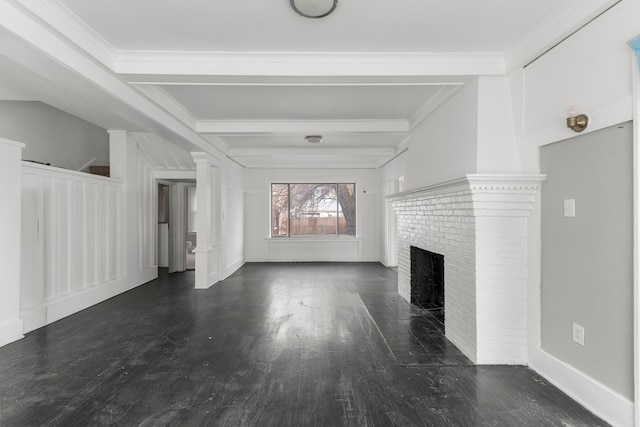 unfurnished living room with a fireplace, wood finished floors, beam ceiling, ornate columns, and crown molding