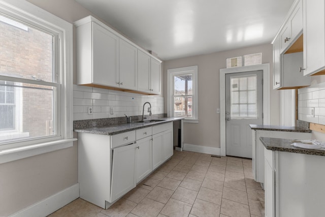 kitchen with white cabinets, baseboards, decorative backsplash, and a sink