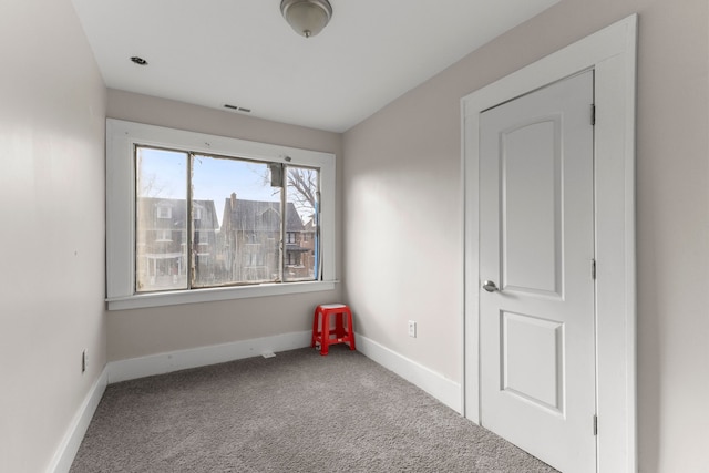 empty room with carpet, visible vents, and baseboards