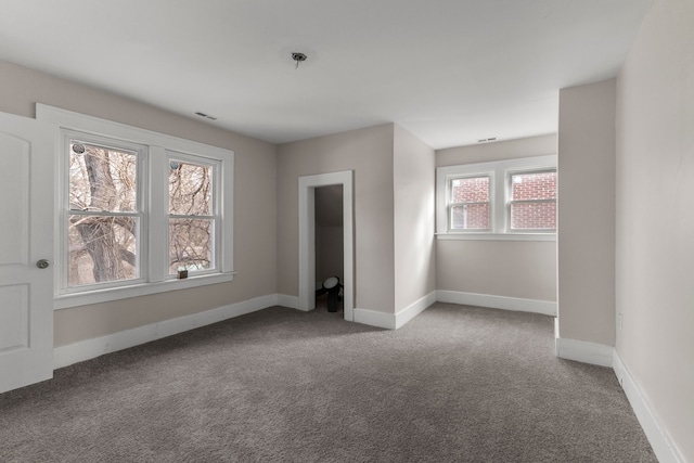 carpeted empty room with visible vents and baseboards