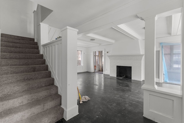 unfurnished living room with beam ceiling, a fireplace, and stairway