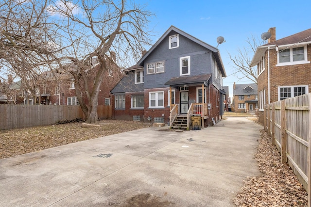 rear view of house featuring brick siding and fence