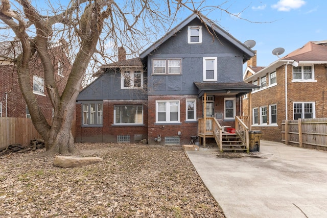 view of front of property with brick siding, a chimney, fence, and stucco siding