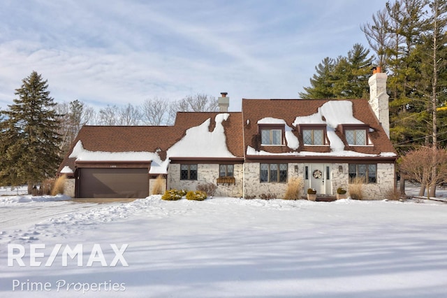 view of front of home featuring an attached garage, stone siding, and a chimney