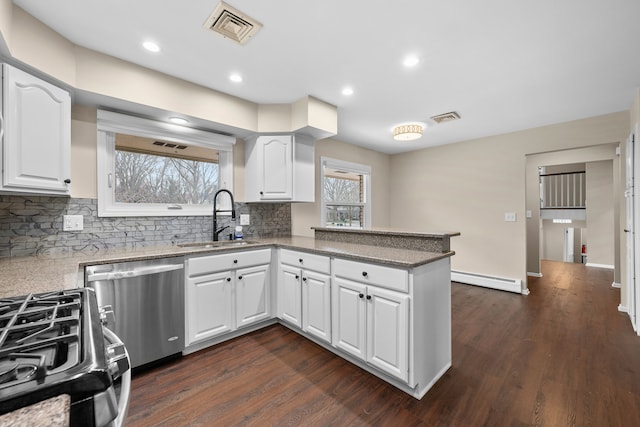 kitchen with dishwasher, a peninsula, a sink, and visible vents