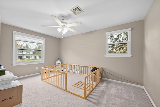 carpeted bedroom featuring a nursery area, visible vents, ceiling fan, and baseboards