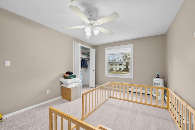 bedroom with carpet floors, a closet, baseboard heating, ceiling fan, and baseboards