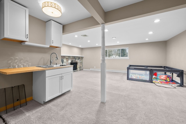 kitchen with open floor plan, a sink, white cabinetry, and light colored carpet