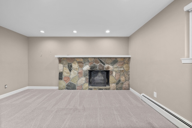 unfurnished living room featuring a baseboard heating unit, carpet, a stone fireplace, and baseboards