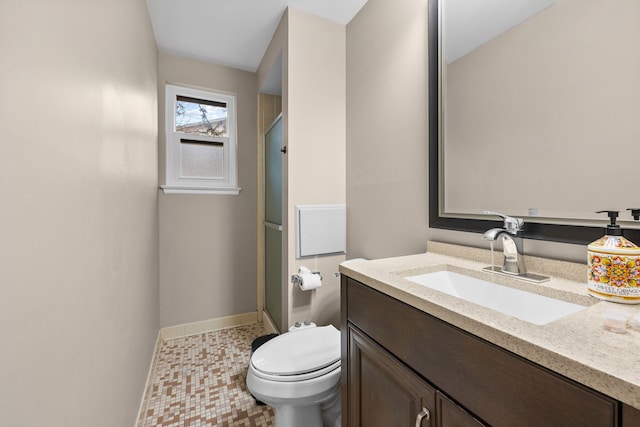 full bath with toilet, a stall shower, baseboards, and vanity