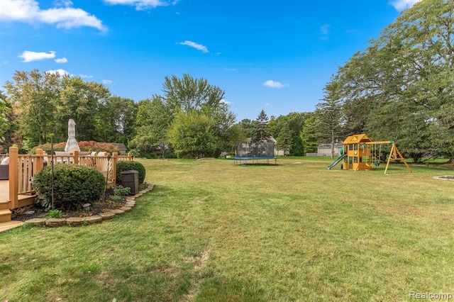 view of yard with a trampoline, a playground, and a deck