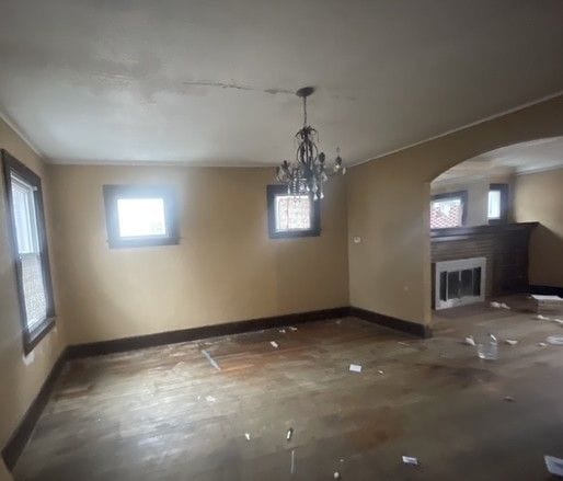 unfurnished dining area featuring a glass covered fireplace, visible vents, arched walkways, and baseboards