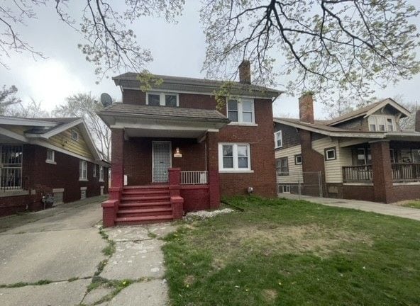 view of front of property with a porch, a front yard, and brick siding