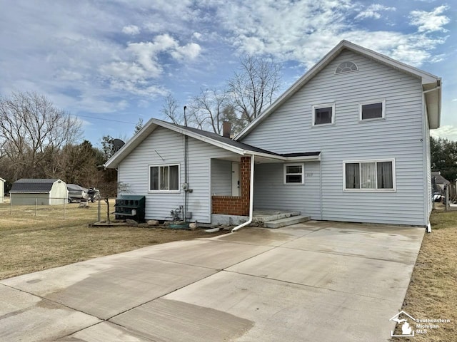 rear view of house featuring driveway, fence, and a yard