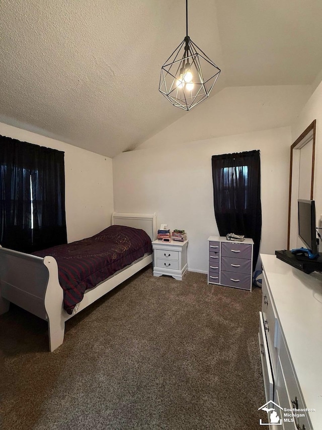 bedroom with lofted ceiling, dark colored carpet, and a textured ceiling