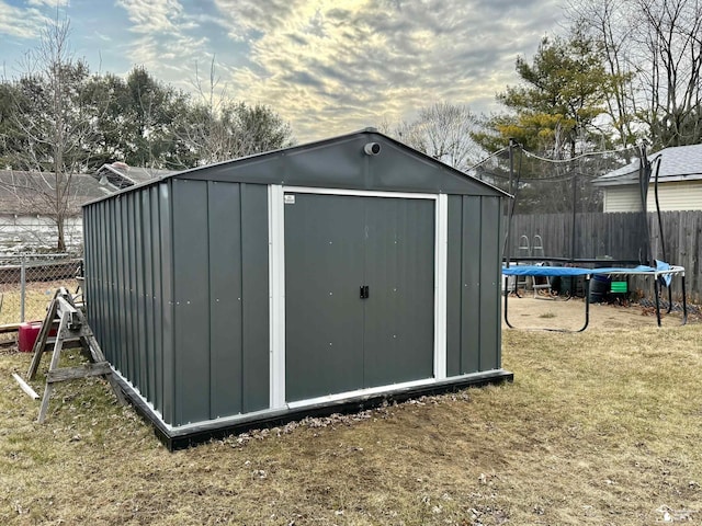 view of shed with a trampoline and a fenced backyard